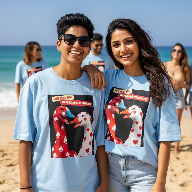 Two friends wearing oversized Gooxit graphic T-shirts on a sunny beach, highlighting modern Gen Z streetwear, oversized fashion, and premium casual clothing.