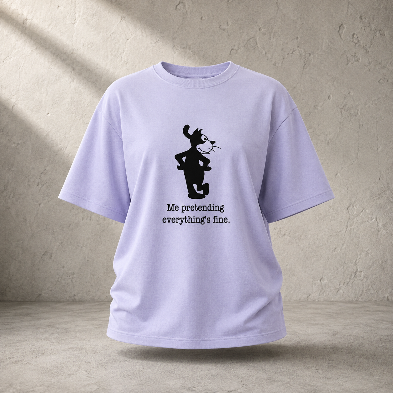 A light lavender crewneck t-shirt with a black graphic of a cartoon cat and the text 'Me pretending everything's fine.' printed on the front, displayed against a textured concrete wall background.