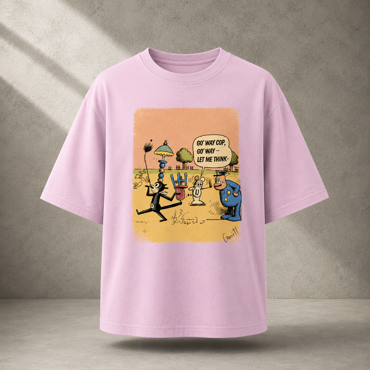 A light pink short-sleeve t-shirt with a colorful cartoon graphic print on the front, displayed against a textured gray concrete wall background.