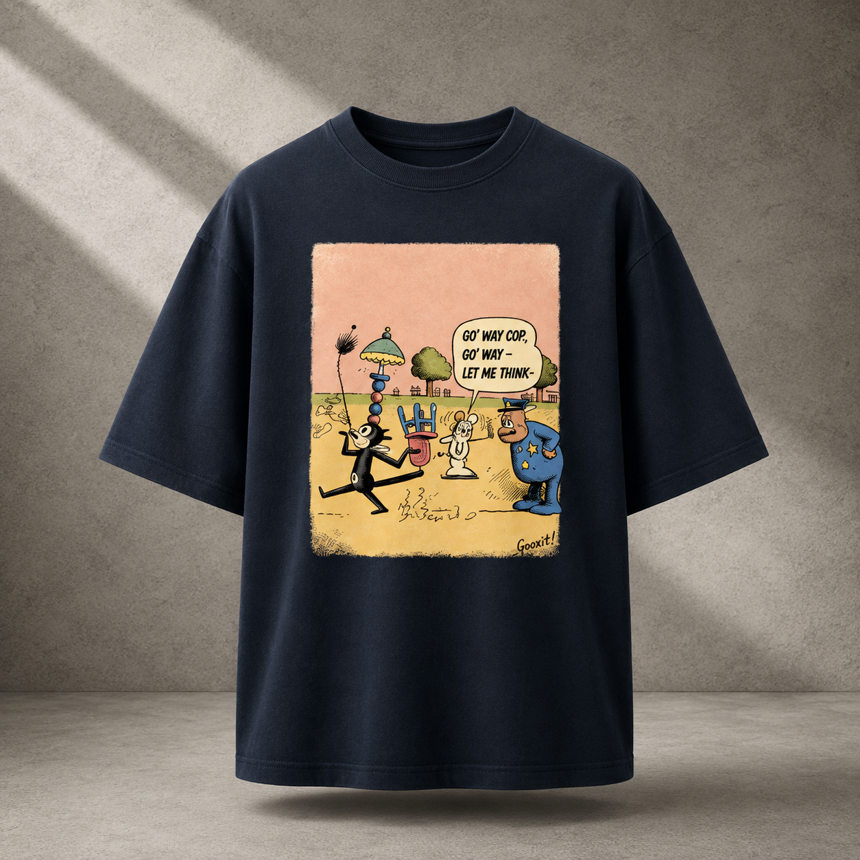 A navy blue short-sleeve t-shirt with a large, colorful cartoon graphic print on the front, displayed against a textured gray concrete wall with diagonal shadows.