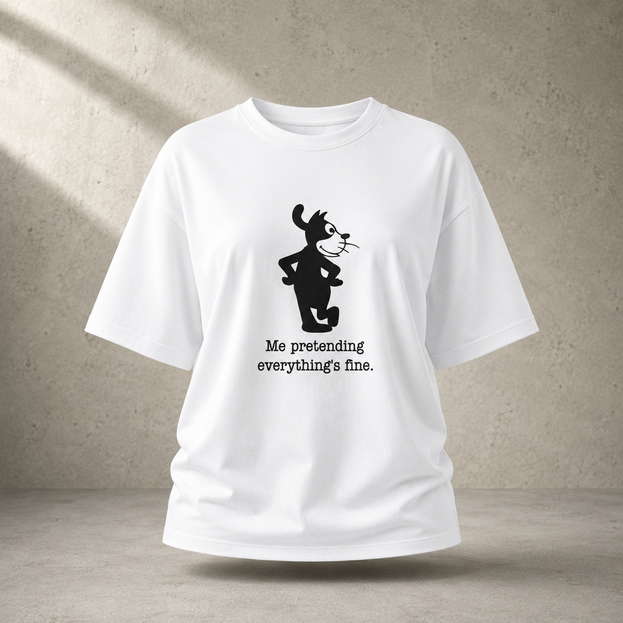 A white short-sleeve t-shirt with a black graphic of a cartoon cat and the text 'Me pretending everything's fine.' printed on the front, shown against a textured concrete wall background.